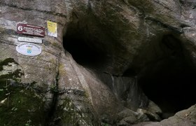 Eingang der Gudenushöhle mit Schildern an der Felswand.