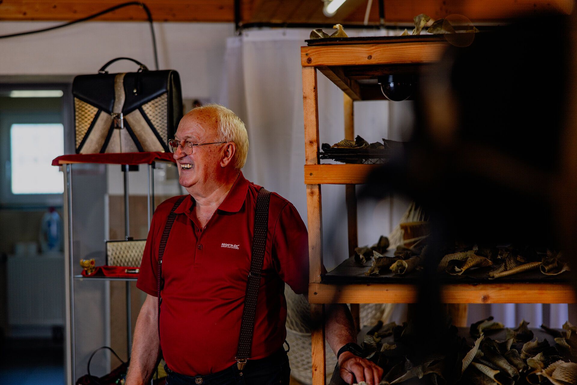 In einer einladenden Werkstatt strahlt die Atmosphäre von Kreativität und Handwerkskunst. Ein erfahrener Handwerker lächelt zufrieden, während er mit Hingabe an einem einzigartigen Produkt aus Fischleder arbeitet. Die Umgebung ist geprägt von traditionellen Werkzeugen und Materialien, die die Leidenschaft für das Handwerk widerspiegeln.