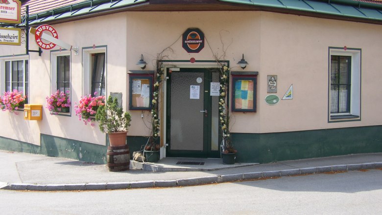 Entrance to a traditional inn with flowers and signs.