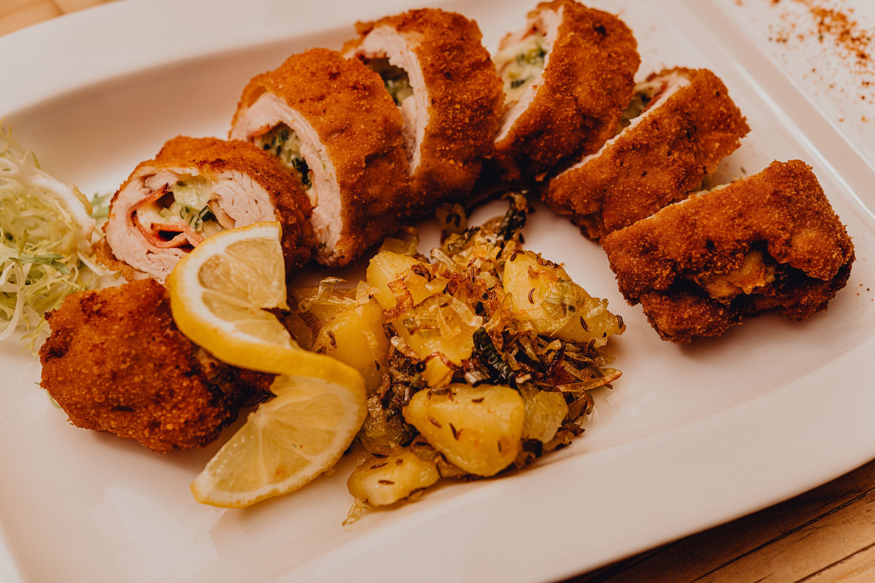 Gefülltes gebackenes Putenfilet mit Kartoffelbeilage und Zitronenscheiben auf einem weißen Teller.