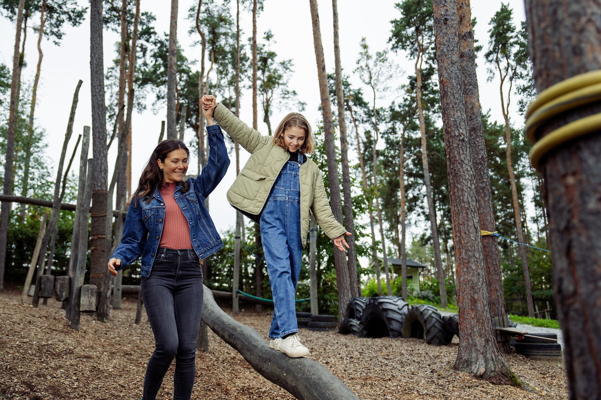 Ein fröhliches Abenteuer erwartet die Familie im Waldviertel, während sie über einen Baumstamm balanciert. Die Kinder lachen und genießen die frische Luft, umgeben von hohen Bäumen und der Schönheit der Natur. Hier wird der Sommer in den Bergen lebendig und unvergesslich.