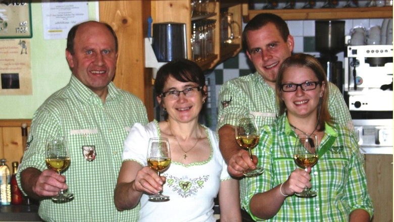 Vier Personen in Tracht stoßen mit Weingläsern an.