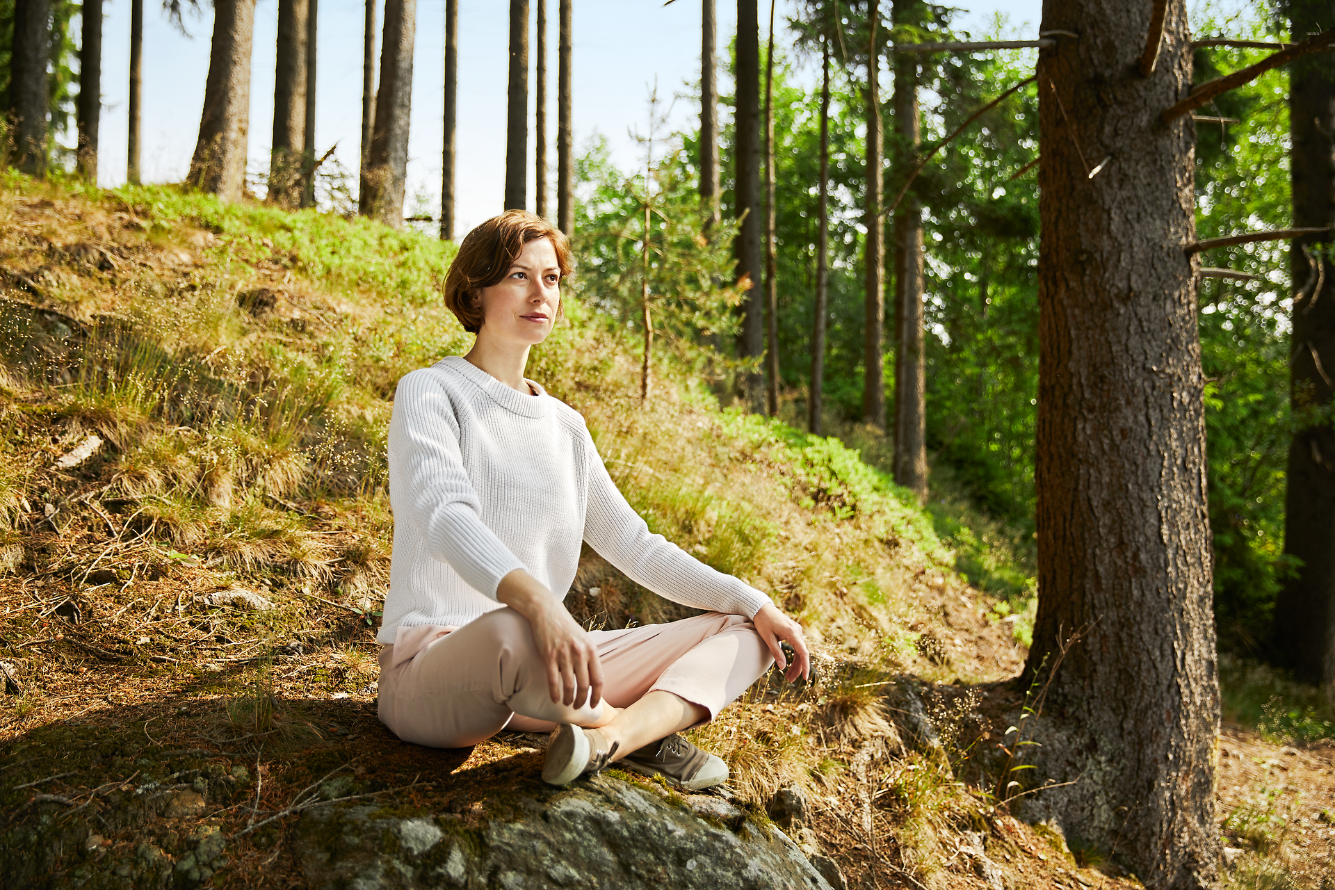 Inmitten der ruhigen Wälder des Waldviertels sitzt eine Frau in meditativer Pose und genießt die friedliche Atmosphäre. Die sanften Sonnenstrahlen durchdringen das Blätterdach und schaffen ein harmonisches Spiel von Licht und Schatten. Diese idyllische Umgebung lädt dazu ein, die Seele baumeln zu lassen und die Natur in vollen Zügen zu erleben.