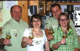 Vier Personen in Tracht stoßen mit Weingläsern an.