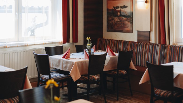 Gemütliches Restaurant mit gedecktem Tisch, roten Servietten und Blumen.