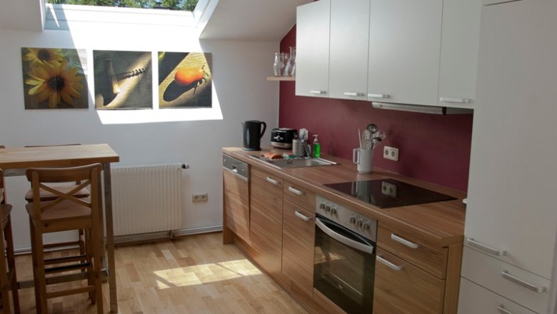 Moderne Küche mit Holzarbeitsplatte, Dachfenster und Wandbildern.