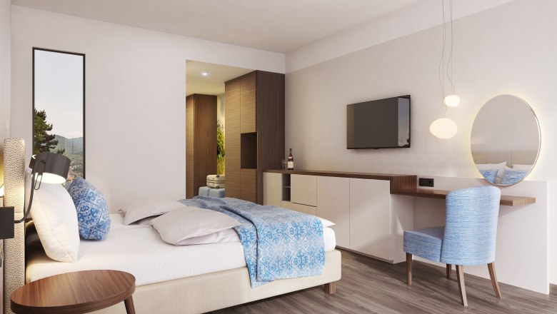 Modern furnished hotel room with double bed, blue chair, wall mirror and flat screen TV.