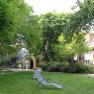 A green inner courtyard with sun loungers and trees, surrounded by buildings.