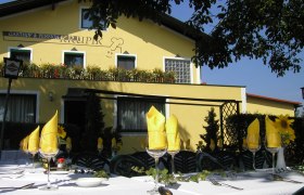 Au&szlig;enansicht des Gasthofs Krupik mit gedecktem Tisch im Vordergrund.