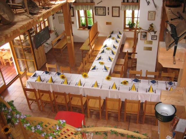 Innenansicht eines Gasthofs mit gedeckten Tischen und Holzstühlen.