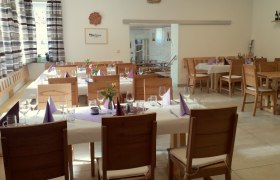 Innenansicht eines gemütlichen Heurigenlokals mit gedeckten Tischen und Holzmöbeln.