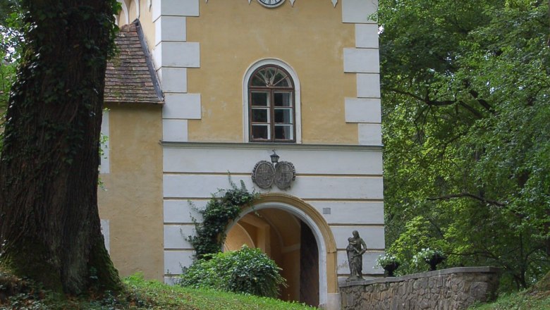 Historisches Gebäude mit Turm und Uhr in einem Waldgebiet.