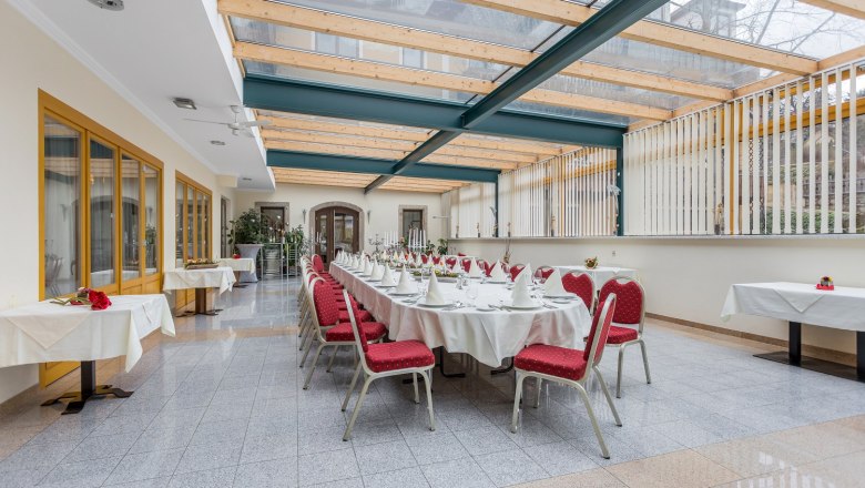 Eleganter Wintergarten mit gedecktem Tisch und roten Stühlen.