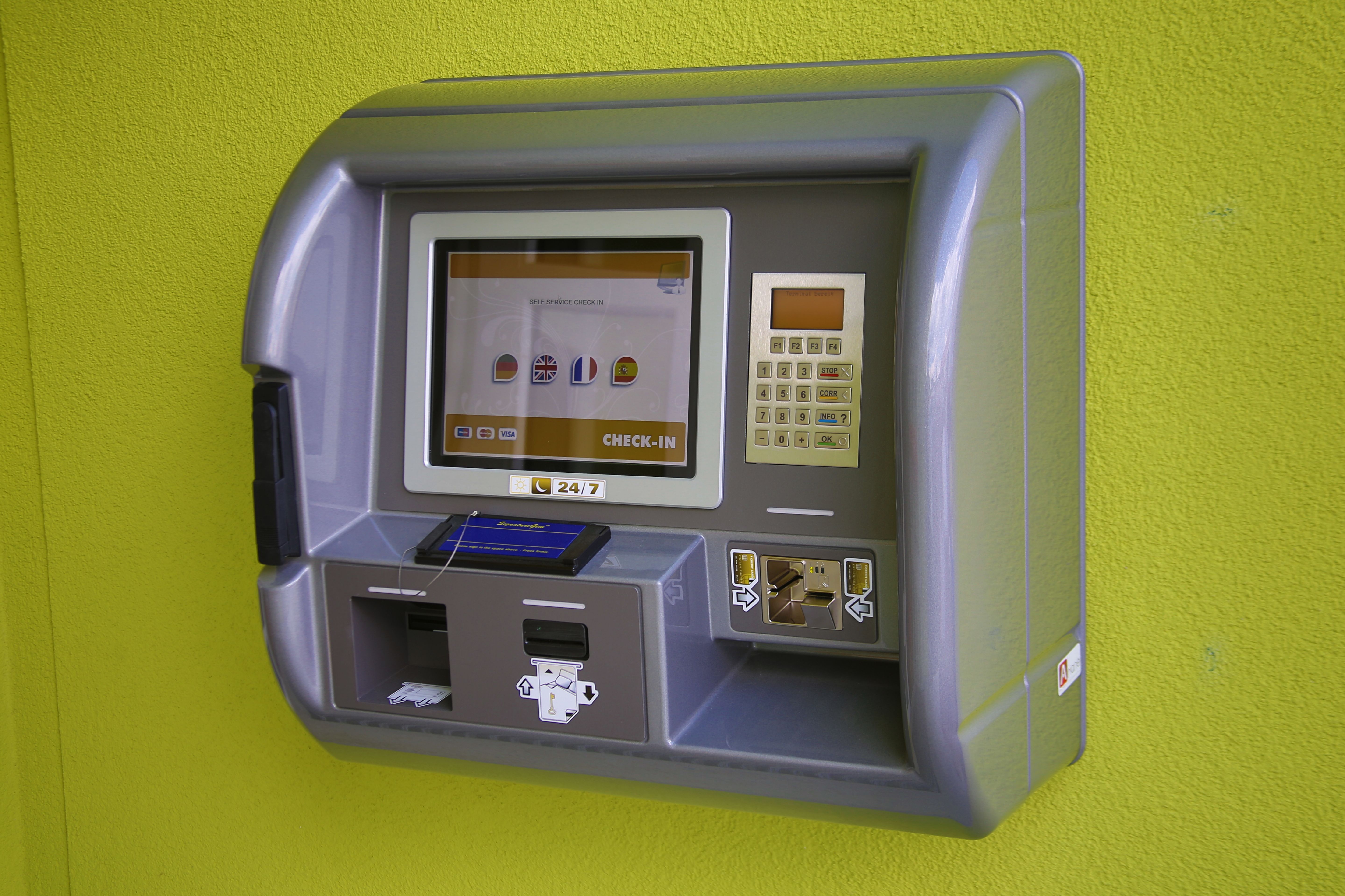 Ein Check-in-Automat an einer grünen Wand.