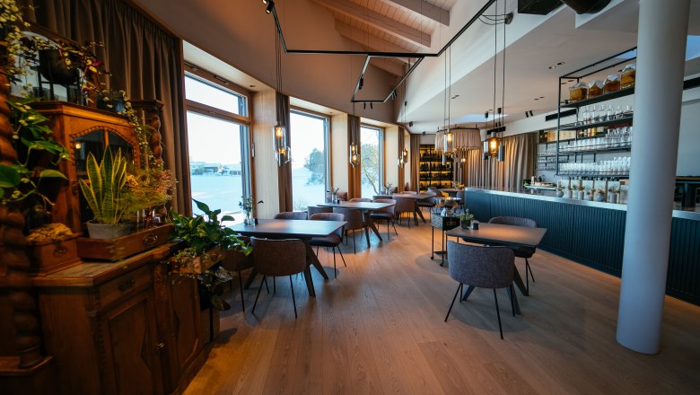 Elegantes Restaurant mit Holzboden, großen Fenstern und stilvoller Einrichtung.