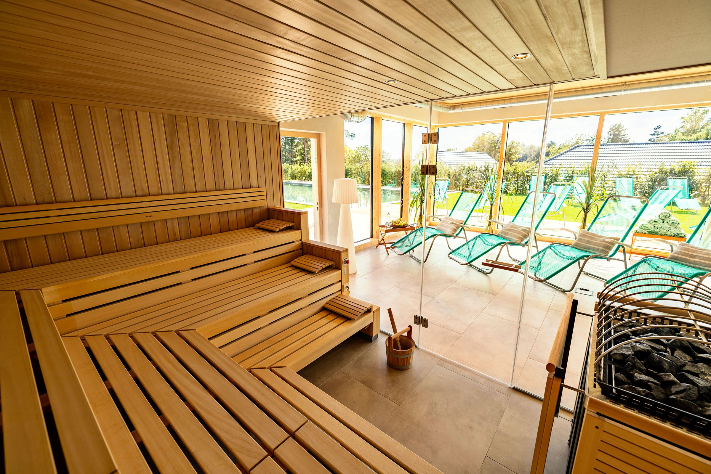 Saunabereich im Golfresort Haugschlag mit Holzsaunen, Liegen hinter Glas und Blick in den Garten.