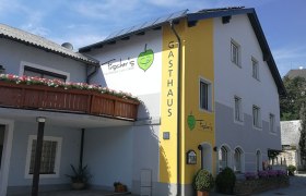 Gasthof Fischer in Albrechtsberg mit gelber Fassade und Blumen.