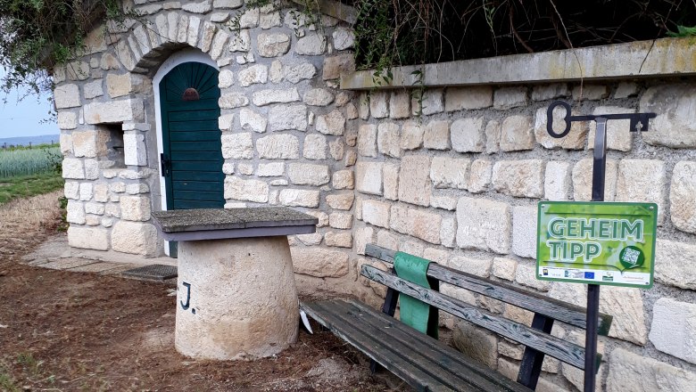 Stone hut with green door, bench and 'Insider tip' sign.
