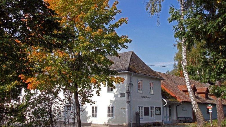 Ein weißes Gebäude mit der Aufschrift 'Heimatmuseum', umgeben von Bäumen mit Herbstlaub.