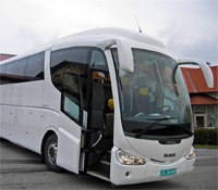 Ein weißer Reisebus der Marke MAN steht mit geöffneter Tür auf einem Parkplatz.