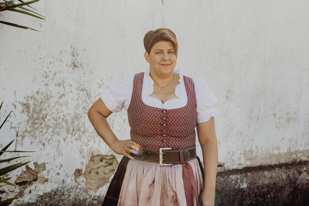 Frau in traditioneller Tracht vor einer weißen Wand.