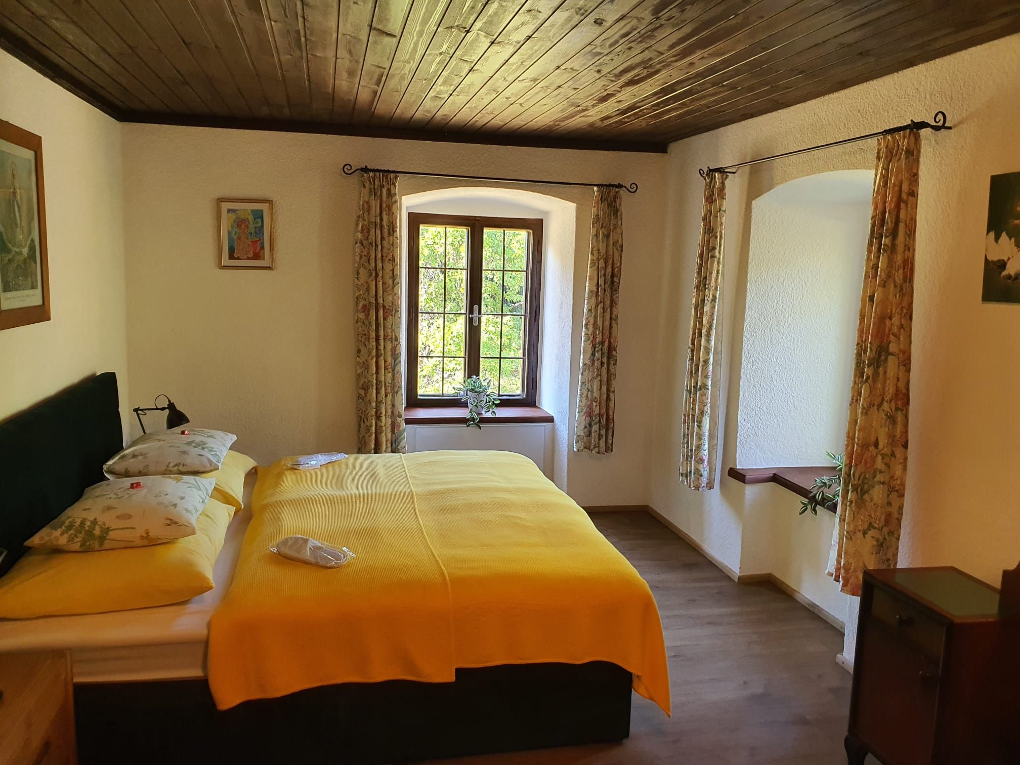Gemütliches Schlafzimmer mit gelber Bettdecke und Holzboden.