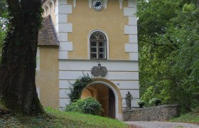 Historisches Gebäude mit Turm und Uhr in einem Waldgebiet.