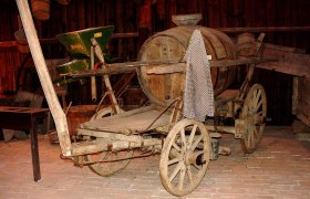 Alte Holzkutsche mit Fass in einem Museum.