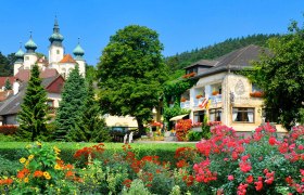 Ein malerisches Hotel mit bunten Blumen im Vordergrund und einem Schloss im Hintergrund.