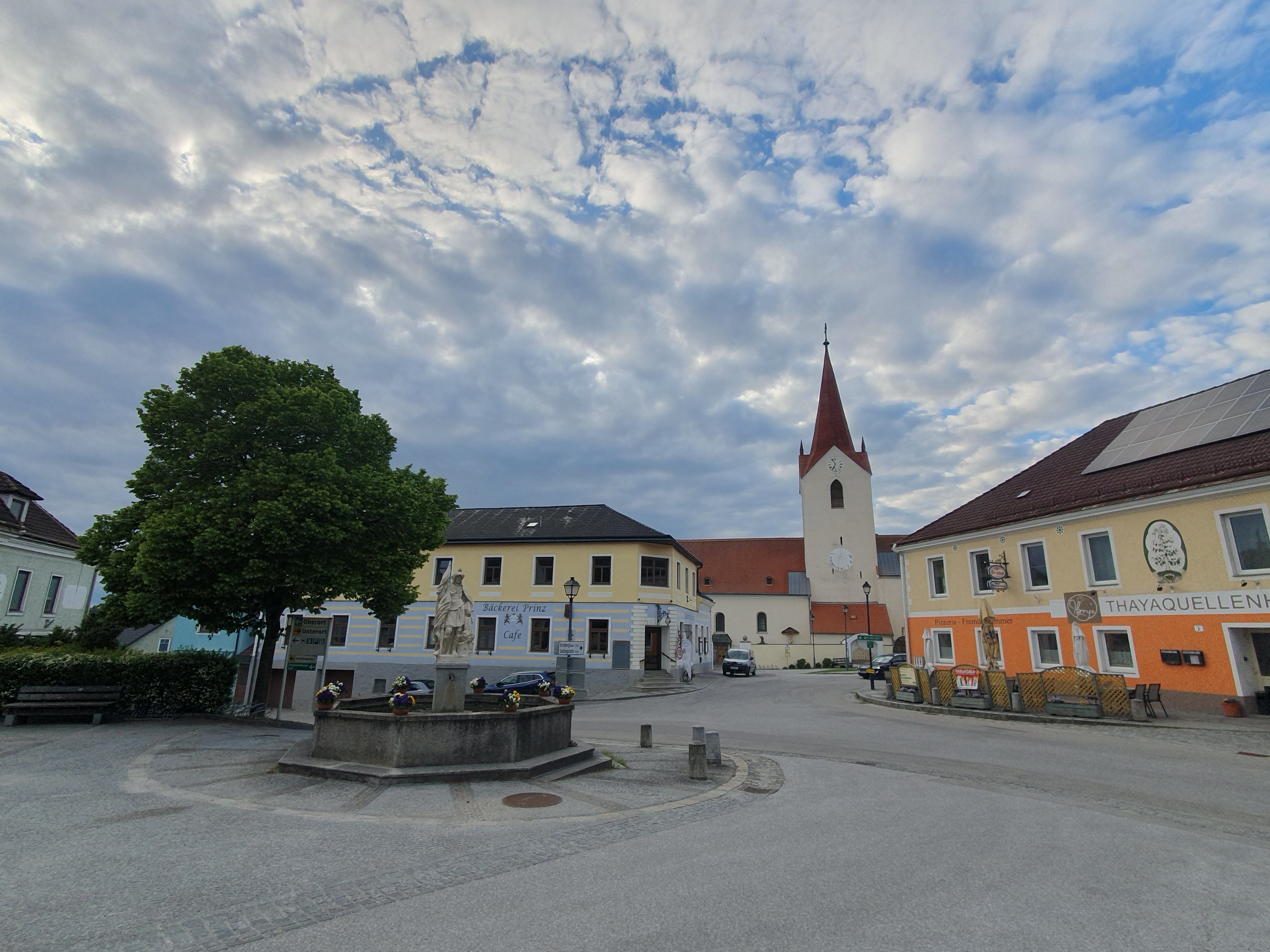 Hauptplatz mit Häusern, einem Platz mit Brunnen und Kirche im Hintergrund