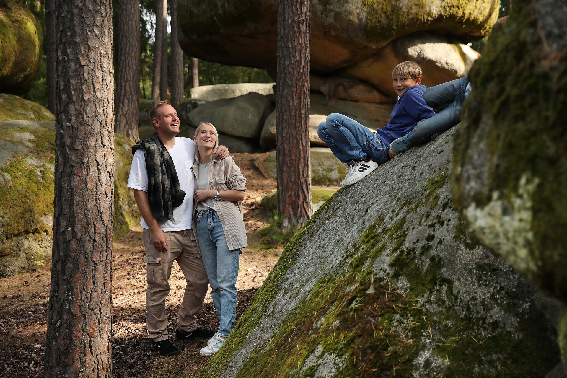 Zwei Burschen liegen auf einem großen Felsen, ihre Eltern stehen am Fuße des Felsen.