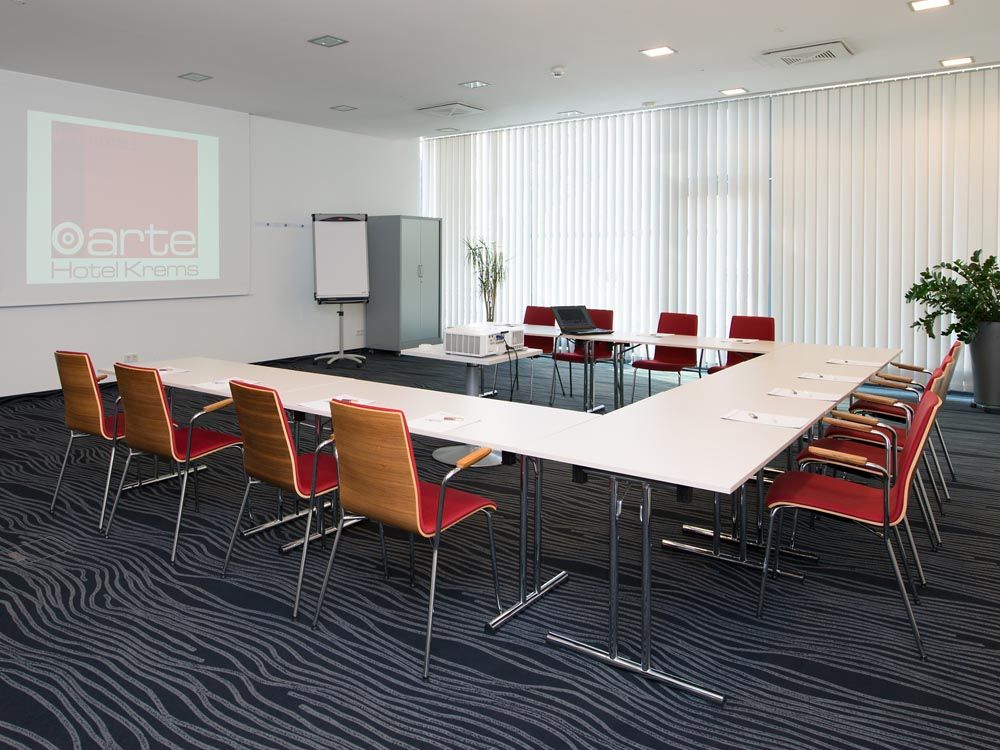Konferenzraum im arte Hotel Krems mit Tischen, Stühlen und Präsentationstechnik.