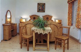 Rustikales Schlafzimmer mit Holzmöbeln, einem Doppelbett, einem Tisch mit Pflanze und einem Spiegel.