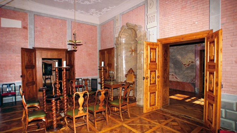 Innenraum des Freimaurermuseums Schloss Rosenau mit Holzmöbeln und dekorativen Wänden.