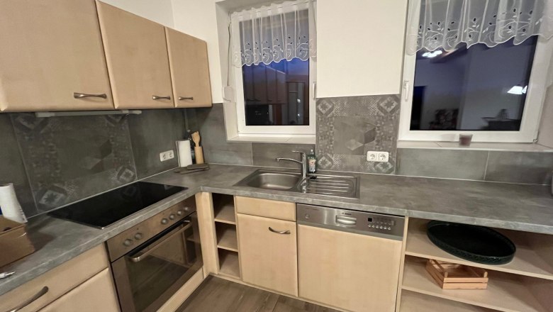 Moderne K&uuml;che mit Holzschr&auml;nken, Elektroherd, Sp&uuml;le und Geschirrsp&uuml;ler.