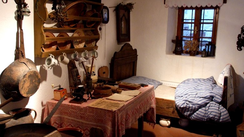 Ein rustikales Zimmer im Heimatmuseum Kautzen mit antiken Möbeln und Küchenutensilien.