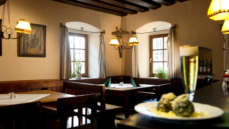 Gemütliches Restaurant mit Holzmöbeln, Bier und Knödeln auf einem Tisch.