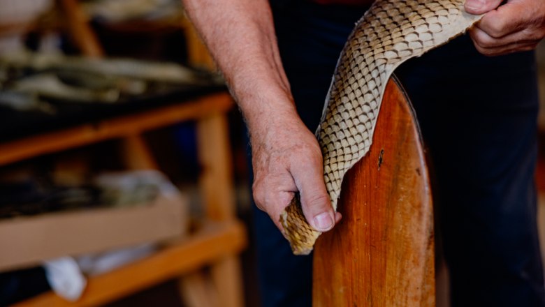 Person bearbeitet Fischleder auf einem Holzwerkzeug.