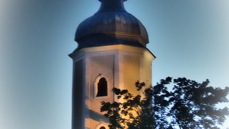 Beleuchteter Kirchturm der Pfarrkirche Sallingberg bei Dämmerung.