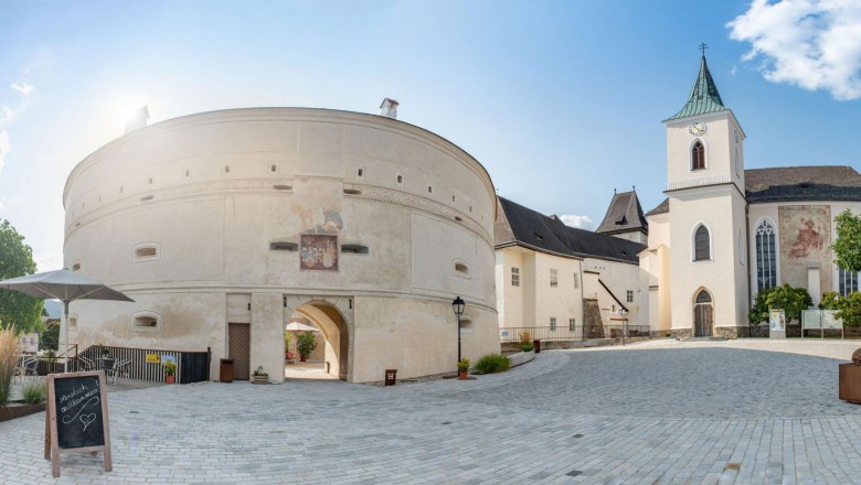 Panoramic view of P&ouml;ggstall Castle with round tower and church in sunny weather.