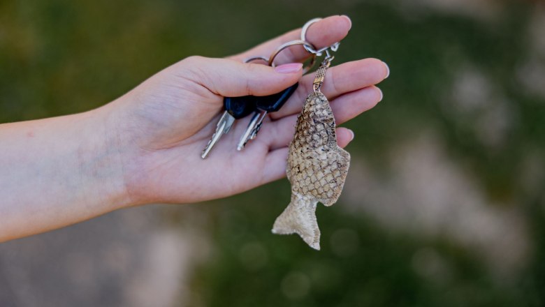 Hand hält Schlüsselbund mit Fischleder-Anhänger.