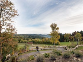 In der sanften H&uuml;gellandschaft entfaltet sich ein malerisches Panorama, das die Seele ber&uuml;hrt. Die bunten Bl&auml;tter der B&auml;ume k&uuml;ndigen den Herbst an und laden zu einem entspannenden Spaziergang ein. Hier, wo die Natur in voller Pracht erstrahlt, findet man den perfekten Ort, um die Ruhe und Sch&ouml;nheit der Umgebung zu genie&szlig;en.