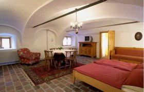 Gemütliches Zimmer mit Holzmöbeln, Doppelbett, Esstisch und Fernseher.