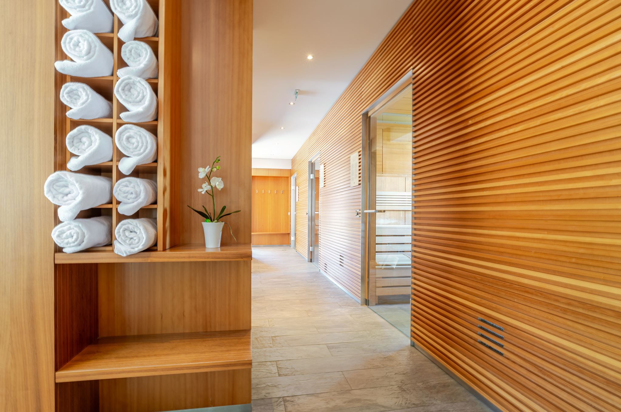 Heller Spa-Flur im Hotel Ottenstein mit Holzverkleidung, Handtuchregal und einer kleinen Orchidee.