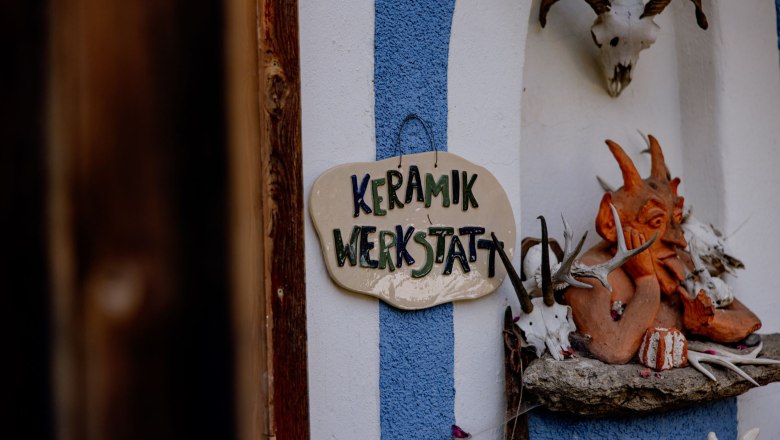 Eingang einer Keramikwerkstatt mit dekorativen Elementen und einem Schild.