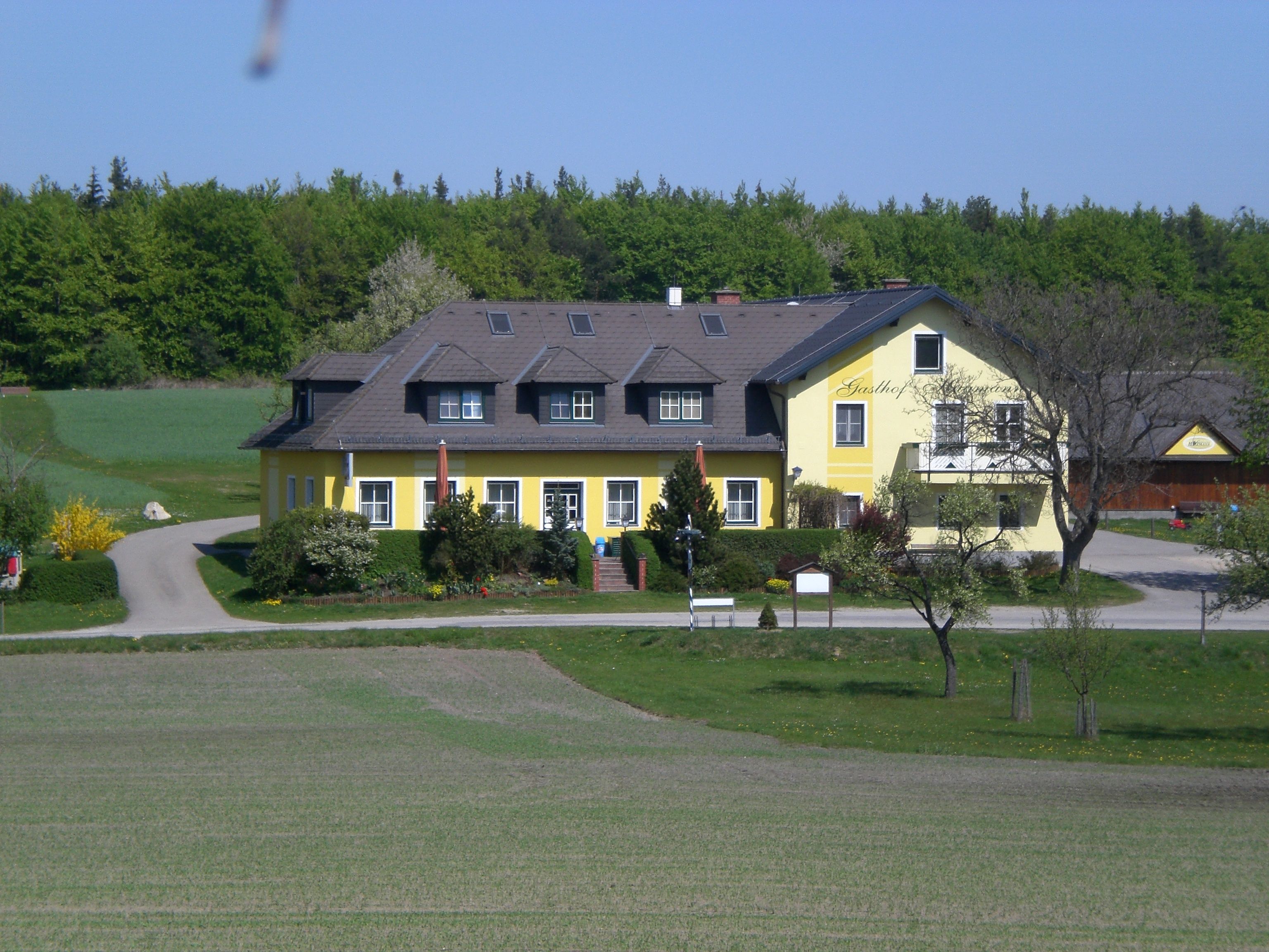 Ein gelber Gasthof in ländlicher Umgebung mit Bäumen und Wiesen.