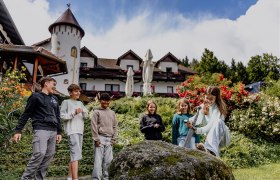 Kinder spielen vor einem Hotel mit einem Schwert in einem Stein.