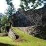 Alte Stadtmauer mit Grünfläche und Bäumen im Sonnenlicht.