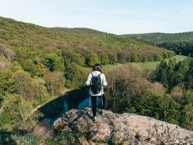 Ein atemberaubender Blick &uuml;ber die sanften H&uuml;gel und das glitzernde Wasser des Flusses schafft eine friedliche Atmosph&auml;re. Die &uuml;ppige gr&uuml;ne Landschaft l&auml;dt Wanderer ein, die Sch&ouml;nheit der Natur zu genie&szlig;en und neue Energie zu tanken. Hier, an diesem Aussichtspunkt, wird jeder Moment zu einem unvergesslichen Erlebnis.