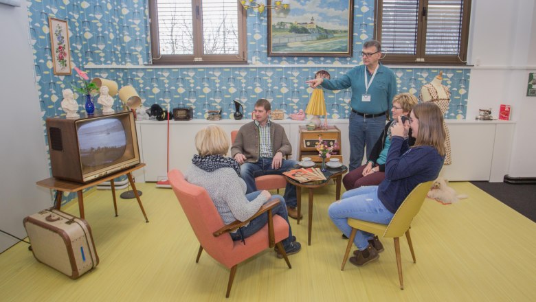 Group of people in a 60's style living room with retro furniture and decoration.